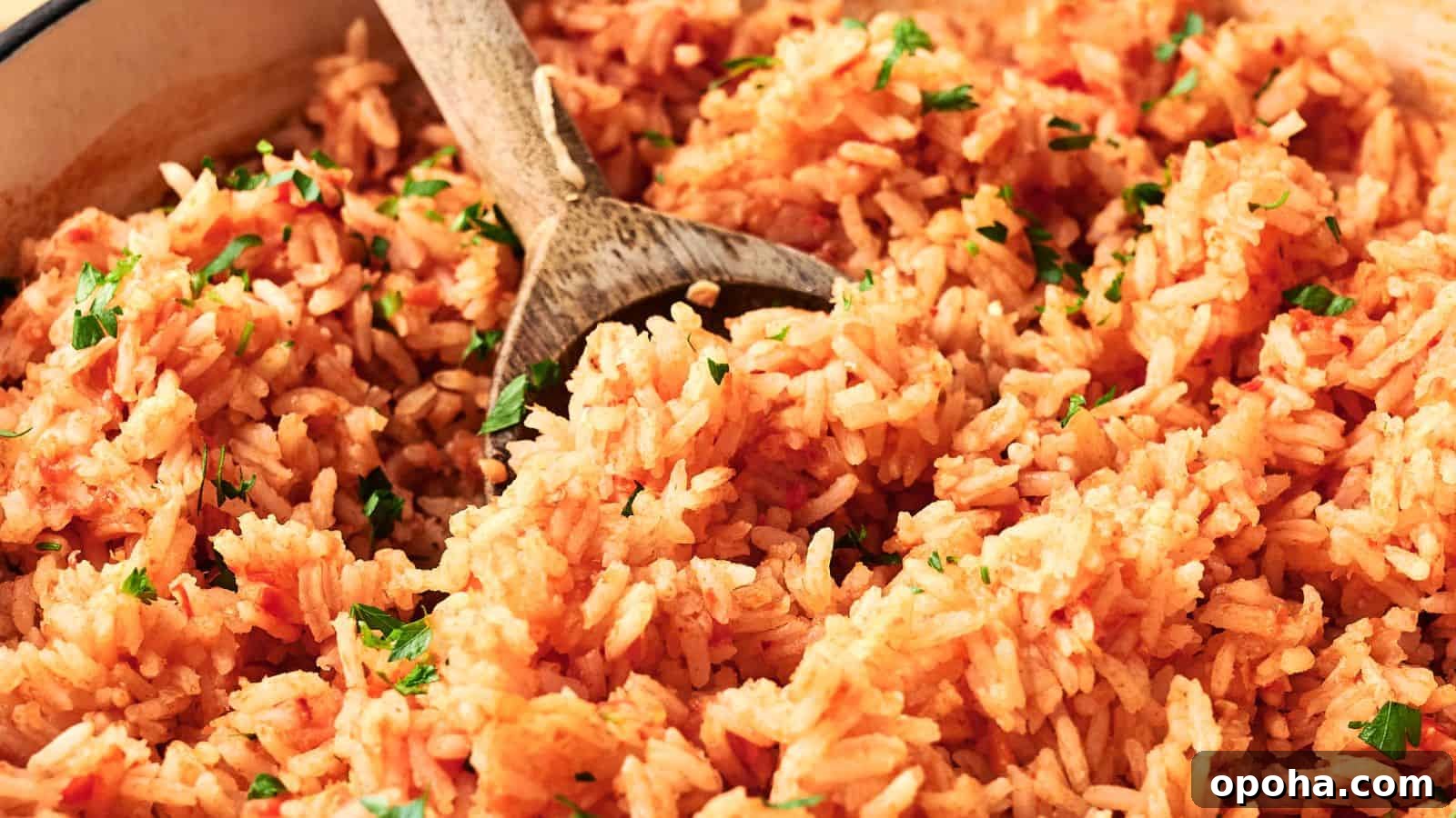 19 Summer Cookout Side Dishes I Make Every Weekend 20 A close-up of cooked Mexican rice with a wooden spoon, garnished with chopped parsley.