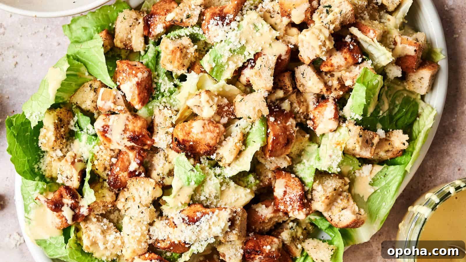 19 Summer Cookout Side Dishes I Make Every Weekend 21 A Caesar salad topped with grilled chicken pieces, croutons, and grated cheese on a bed of romaine lettuce. Dressing is served on the side.