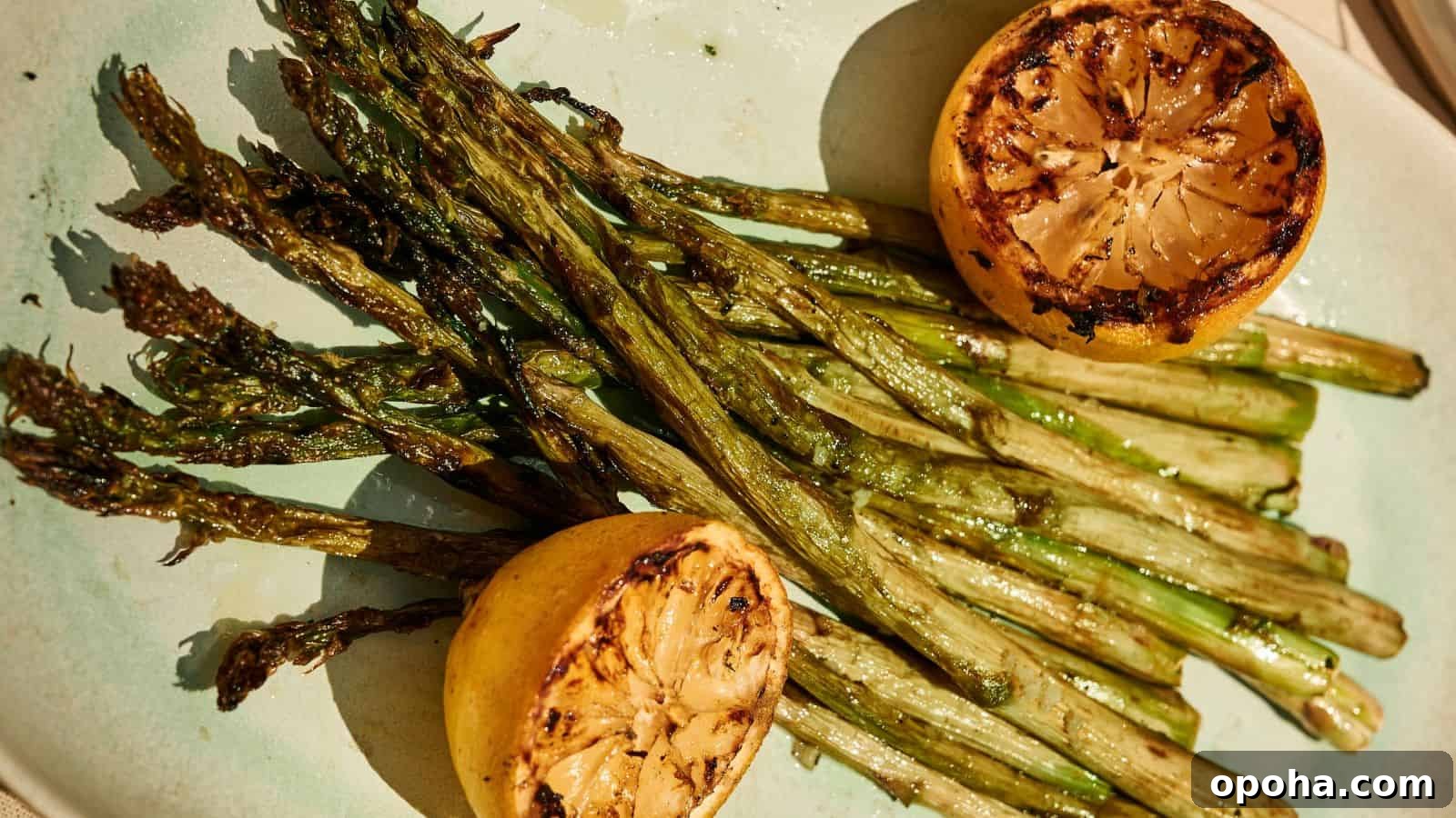 19 Summer Cookout Side Dishes I Make Every Weekend 7 Grilled asparagus spears served on a plate with two charred lemon halves.