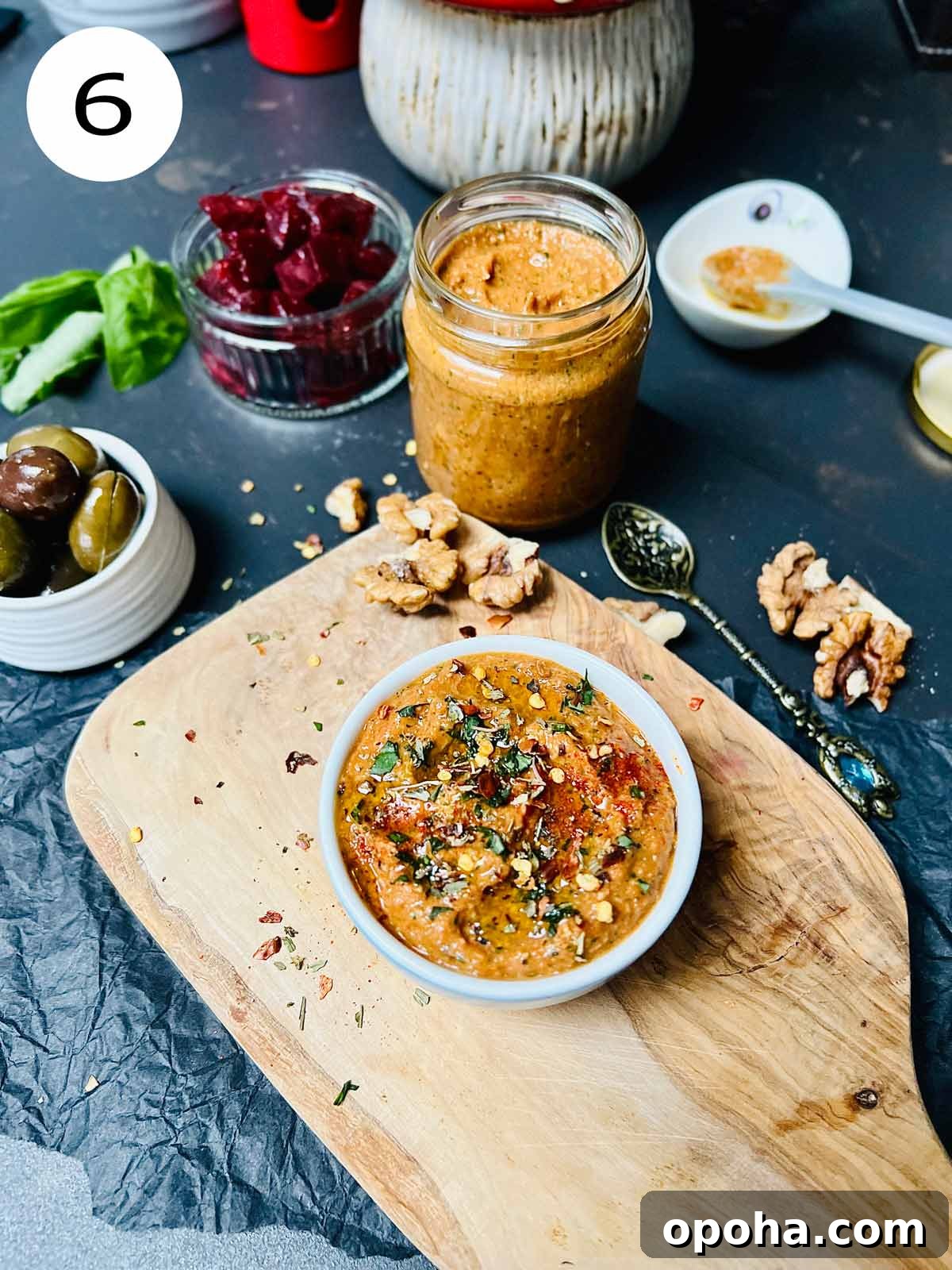 Red pepper sauce in a little serving dish on a wooden chopping board.
