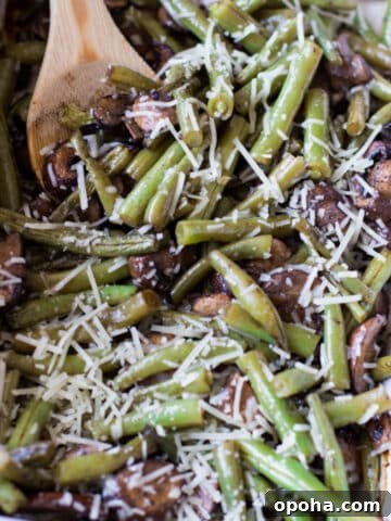 Wooden spoon stirring pan of green beans.