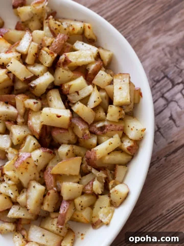 White bowl containing roasted potatoes.