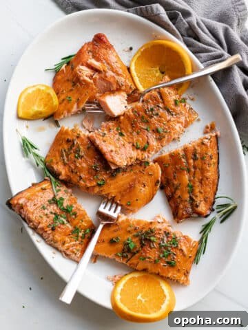 White plate filled with smoked salmon topped with rosemary.