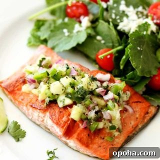 Filet of salmon topped with cucumber lime salsa, salad on side.
