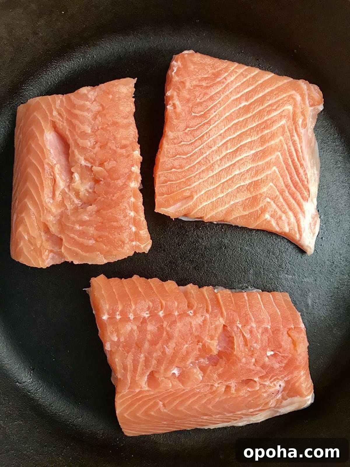 Pan-Seared Salmon with Refreshing Cucumber Salad 4 3 salmon filets searing in a skillet.