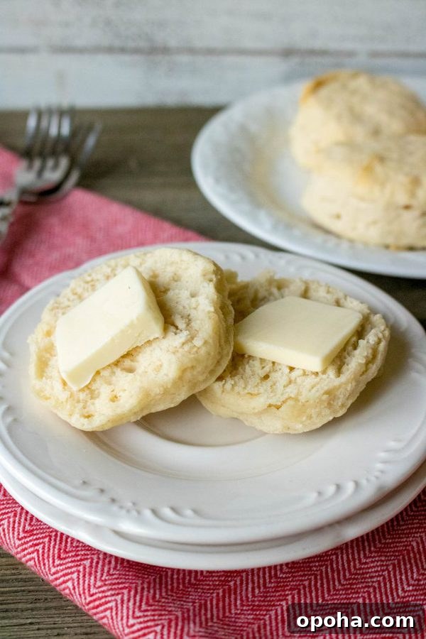 Flaky Southern Buttermilk Biscuits Recipe for Perfect Layers 2 a buttermilk biscuit cut in half and topped with a large pat of butter.