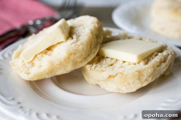 Flaky Southern Buttermilk Biscuits Recipe for Perfect Layers 3 a closeup of buttermilk biscuits topped with butter on a white plate.
