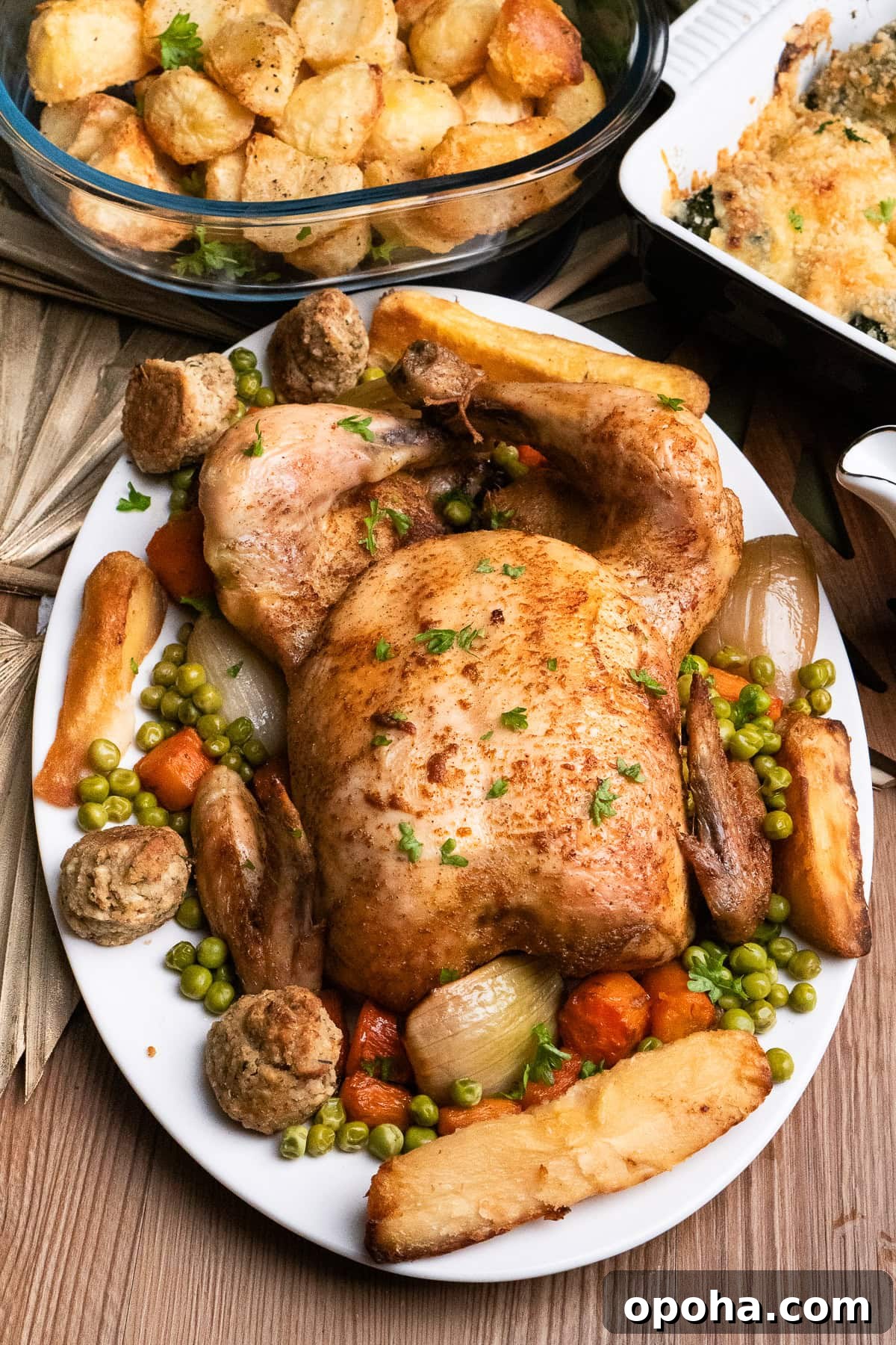 Tender Whole Chicken in a Slow Cooker: Juicy, Simple Recipe 2 Slow cooker roast chicken served on a white platter plate with the carrots and onions it was cooked with, as well as all the trimmings, yorkshire puddings, parsnips,roast potatoes, stuffing and peas.