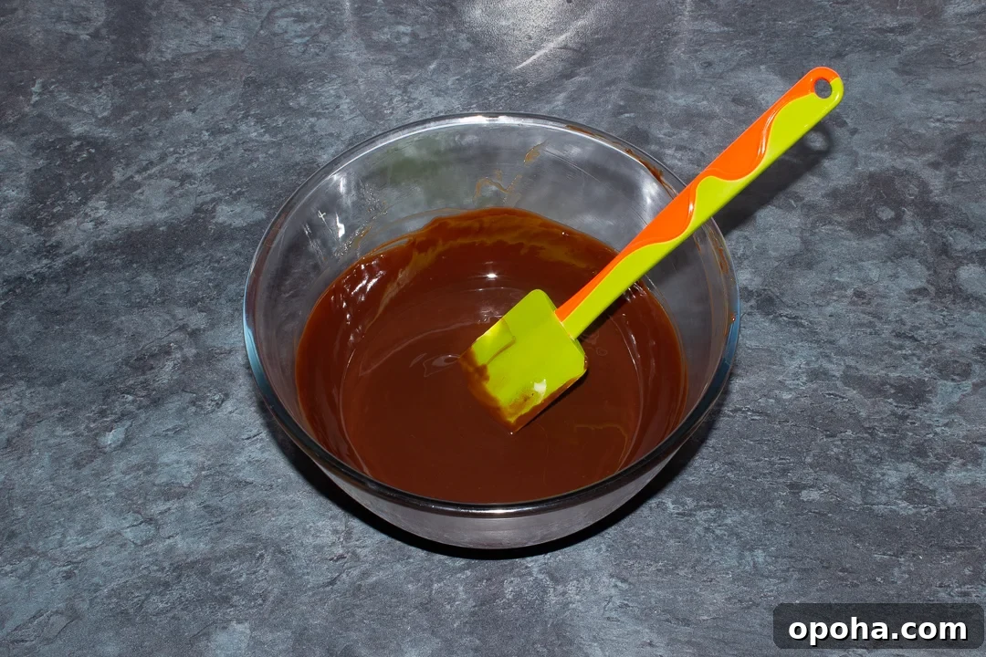 Halloween Millionaire Brownies: Rich Chocolate Caramel Treats 14 Melted dark chocolate and butter in a glass bowl on a kitchen worktop.