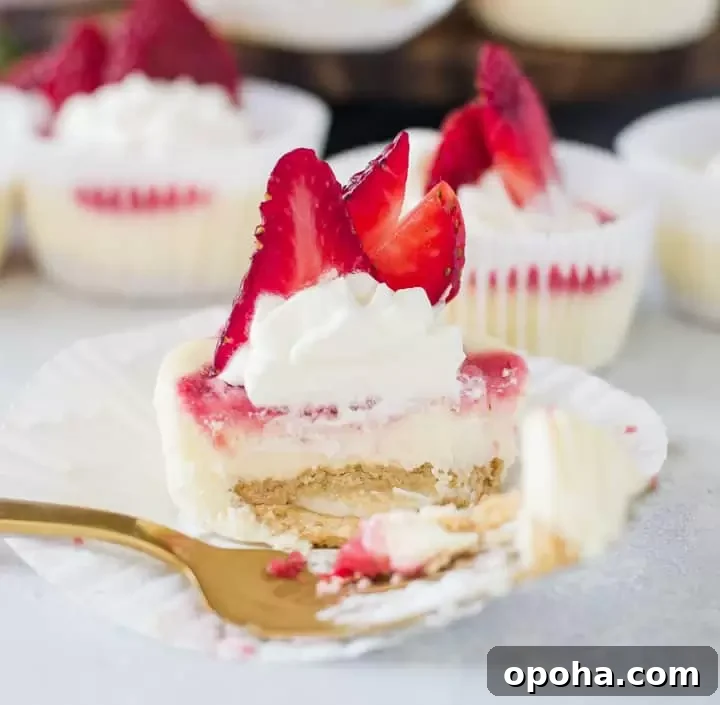 Strawberry Cheesecake Cupcakes Recipe — Creamy Strawberry Swirl 6 one of the strawberry cheesecake cupcakes with a fork taking a bite out of it