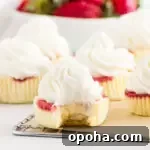 Strawberry Cheesecake Cupcakes Recipe — Creamy Strawberry Swirl 7 cheesecakes on a wire rack with a bowl of strawberries in the background