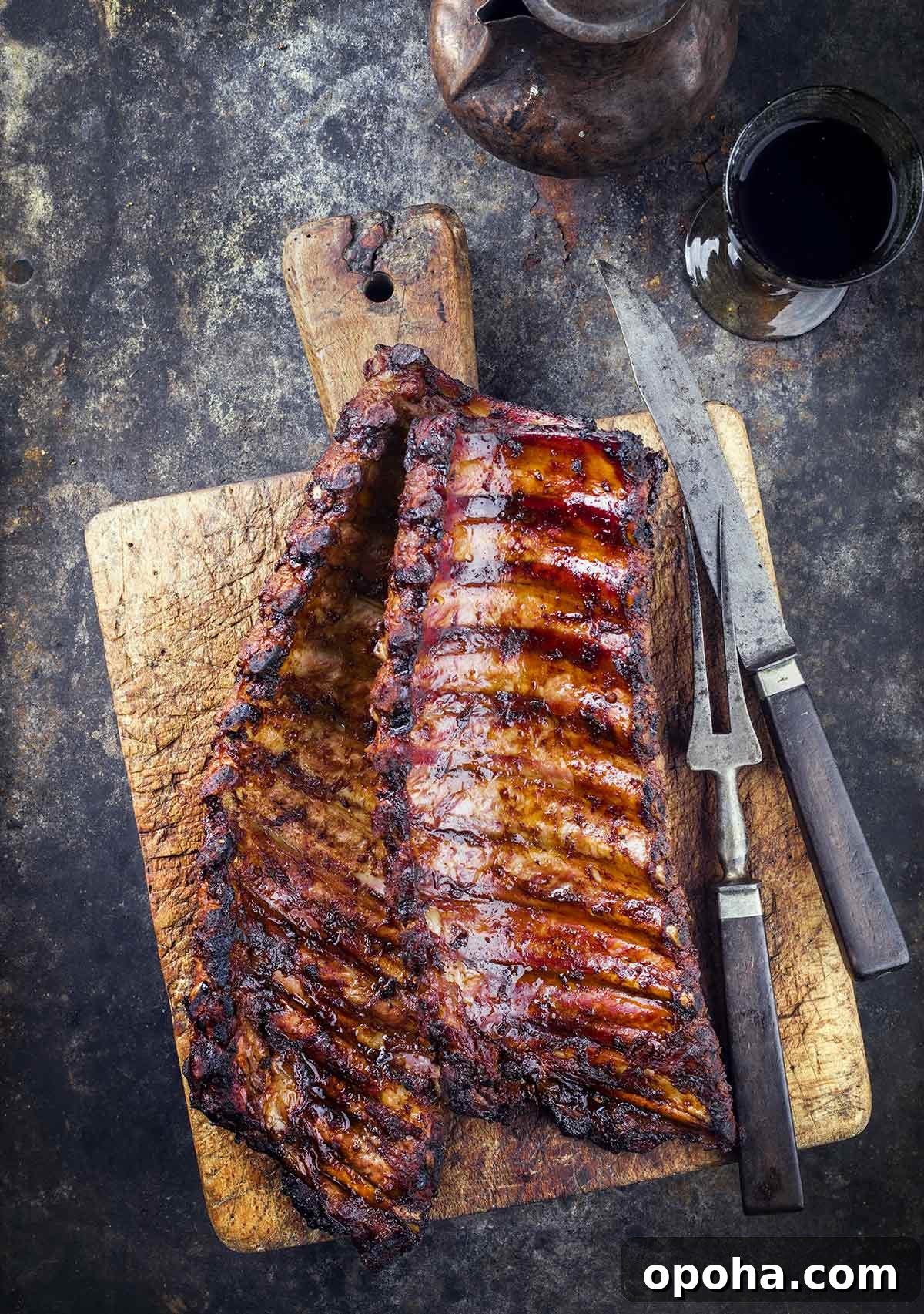 A wooden cutting board topped with two rack of smoked pork ribs.