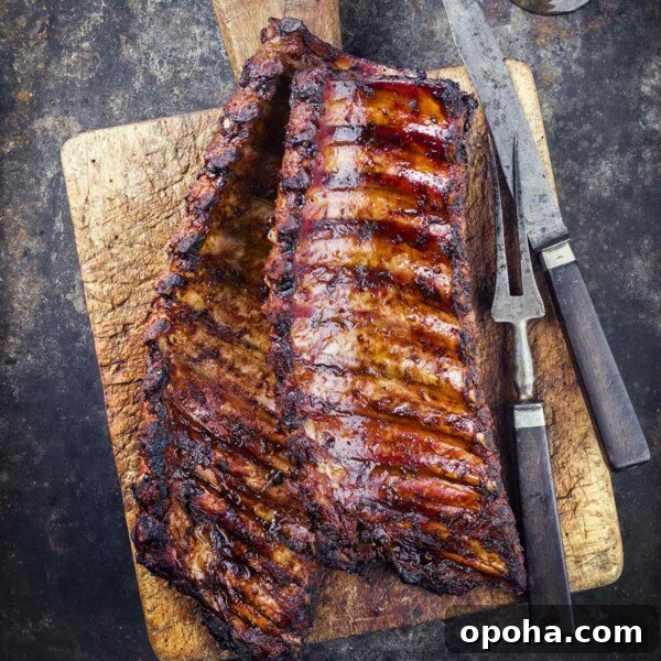 A wooden cutting board topped with two rack of smoked pork ribs.