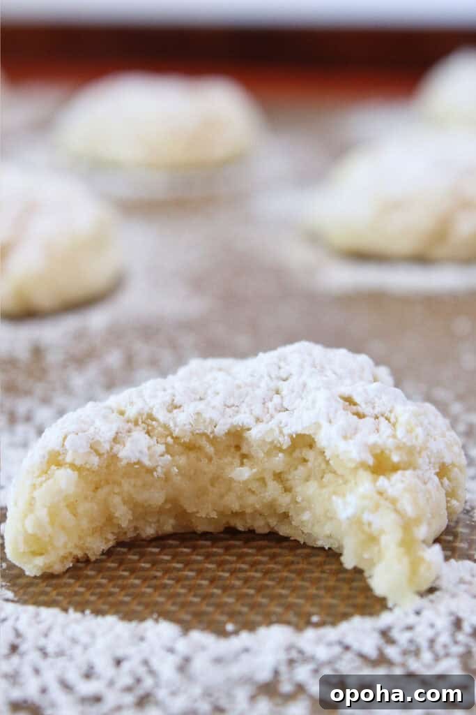 Cream cheese cookies on a baking sheet with powdered sugar.