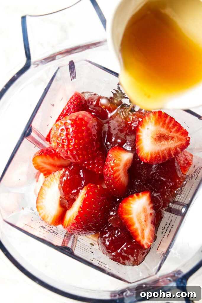 Adding strawberries and honey to a blender.