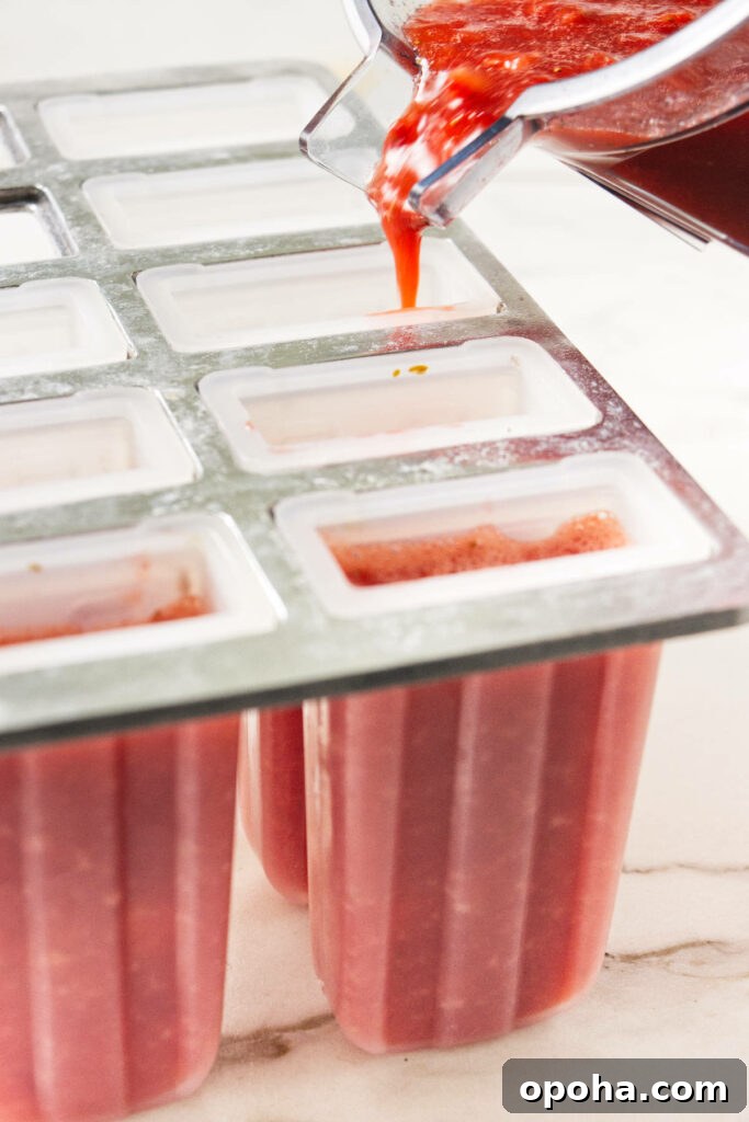 Pouring strawberry puree into popsicle molds.