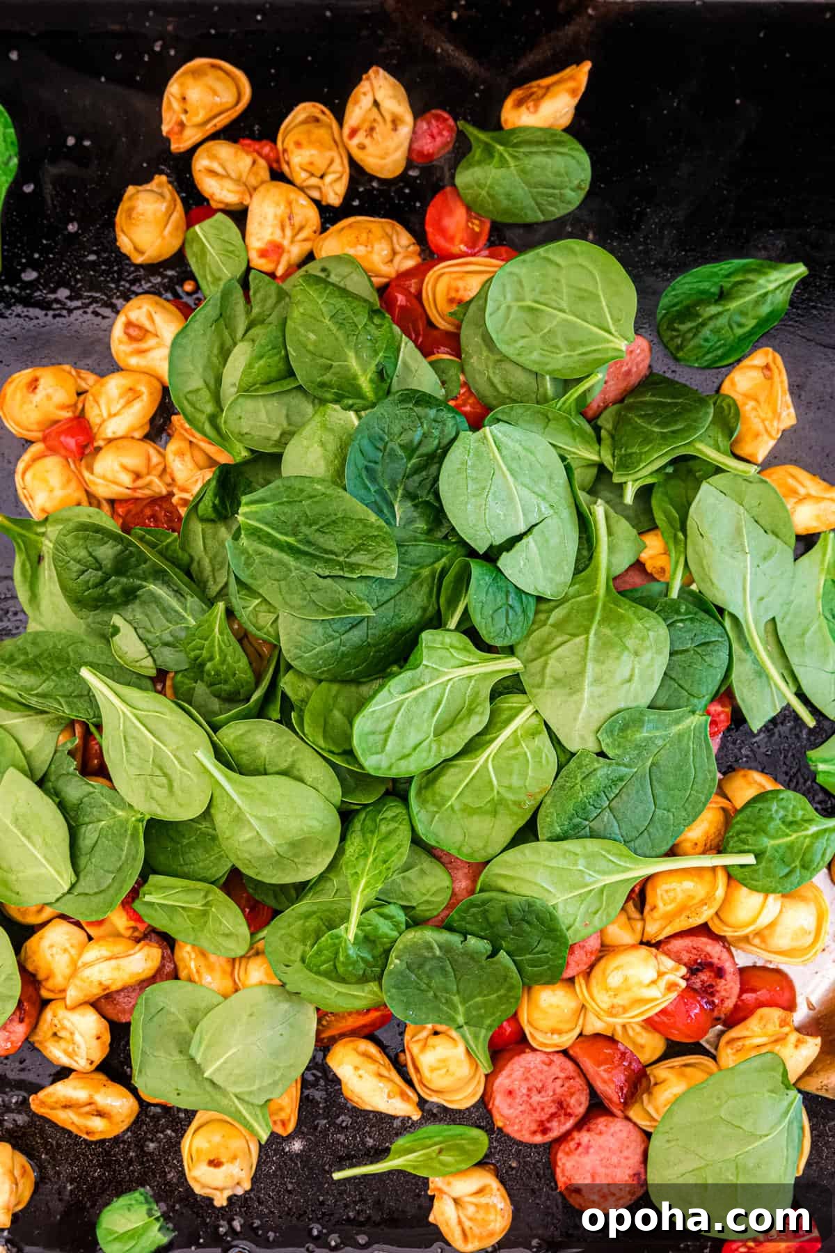 Crispy Blackstone Tortellini Skillet with Garlic Butter Sauce 6 Adding spinach on the Blackstone griddle for Blackstone Tortellini recipe