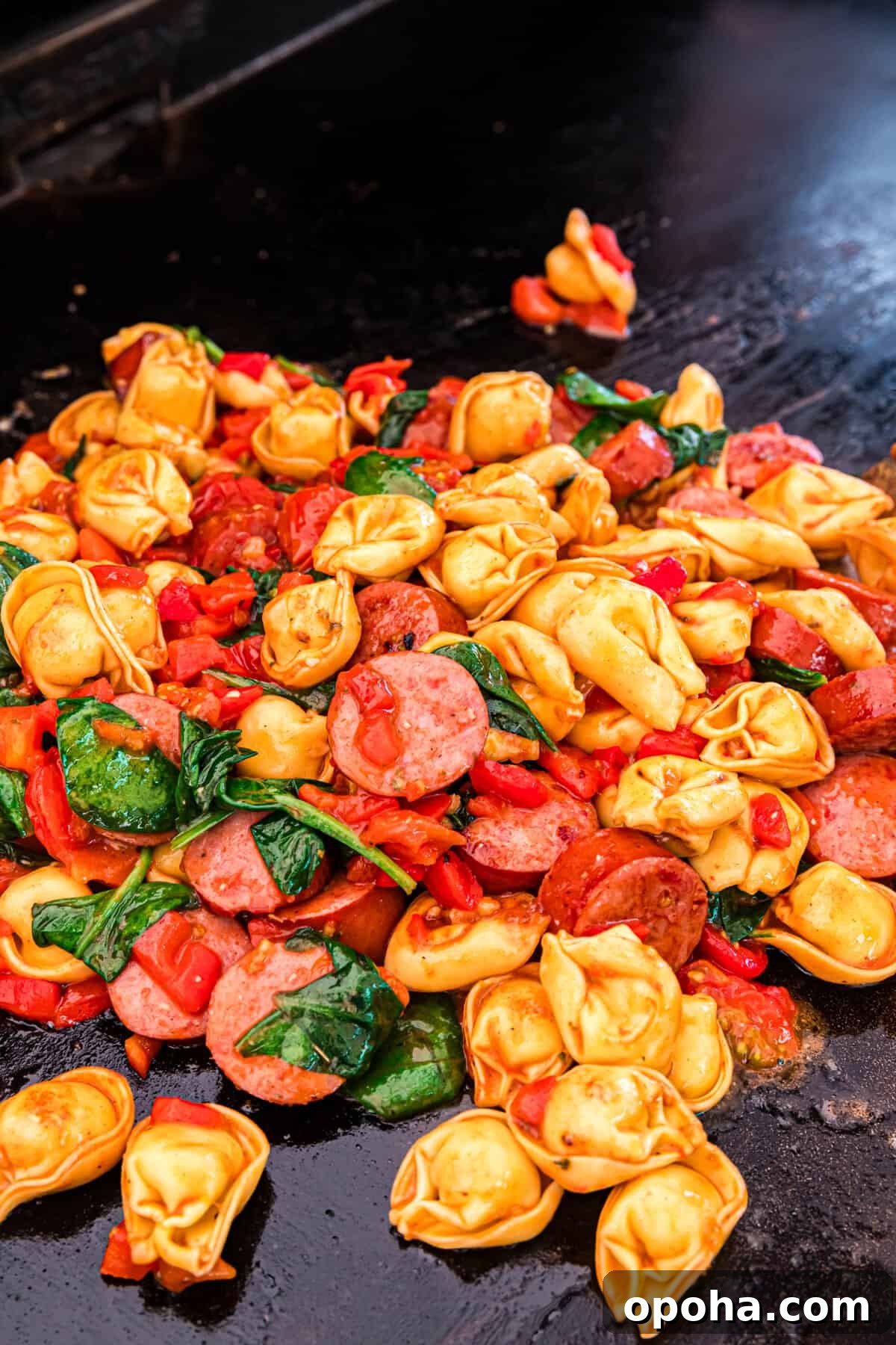 Crispy Blackstone Tortellini Skillet with Garlic Butter Sauce 7 Tossing the ingriedents for Blackstone Tortellini recipe to toss