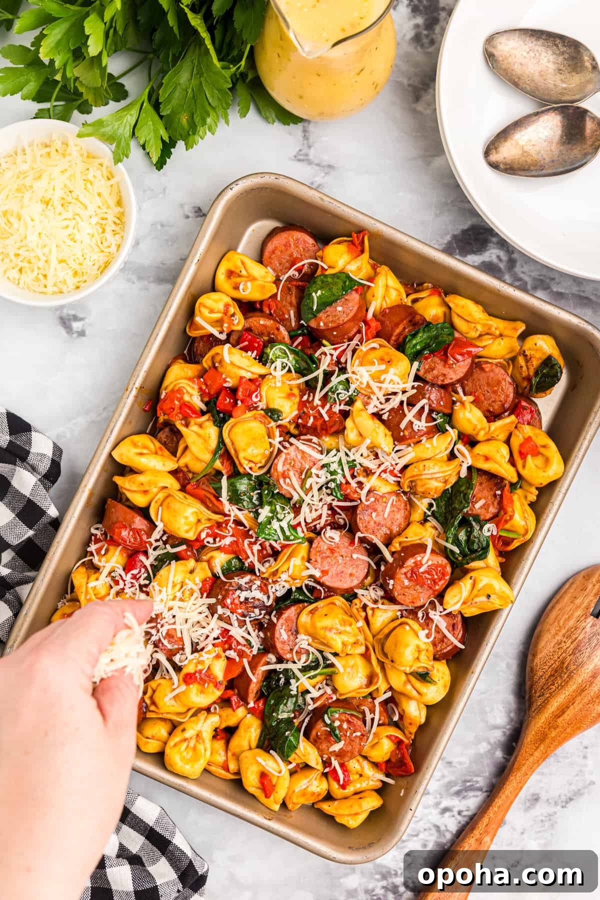 Crispy Blackstone Tortellini Skillet with Garlic Butter Sauce 8 Adding shredded Parmesan cheese to Blackstone Tortellini on grilling pan
