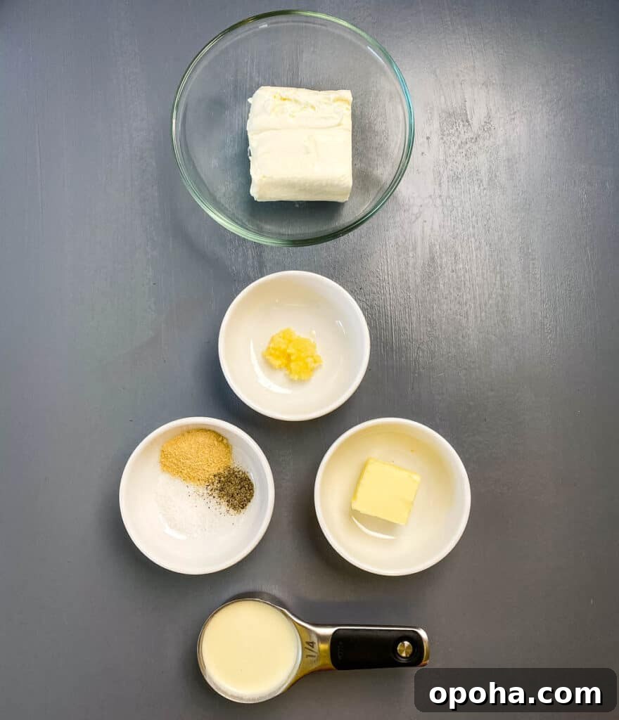 cream cheese garlic, butter, heavy cream, and seasonings in separate bowls on a flat surface