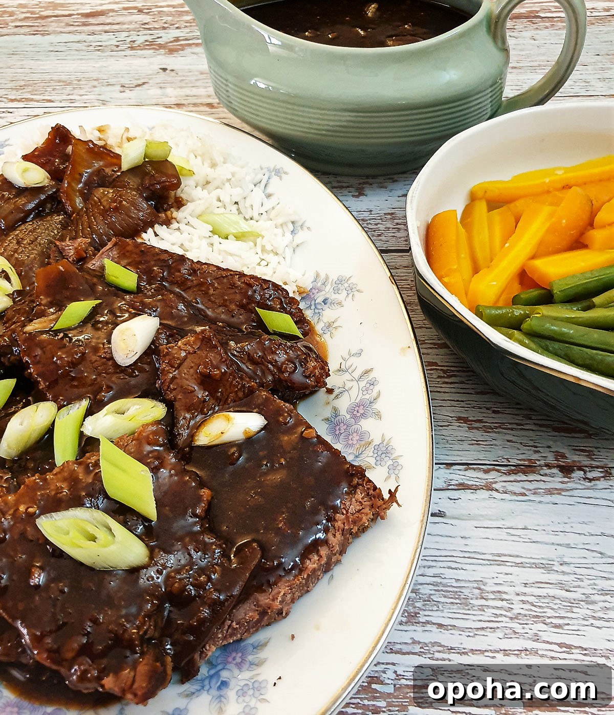 Slow-Cooker Mongolian Roast Beef Recipe for Tender, Savory Meat 9 Slices of mongolian beef on a serving plate next to a bowl of vegetables.