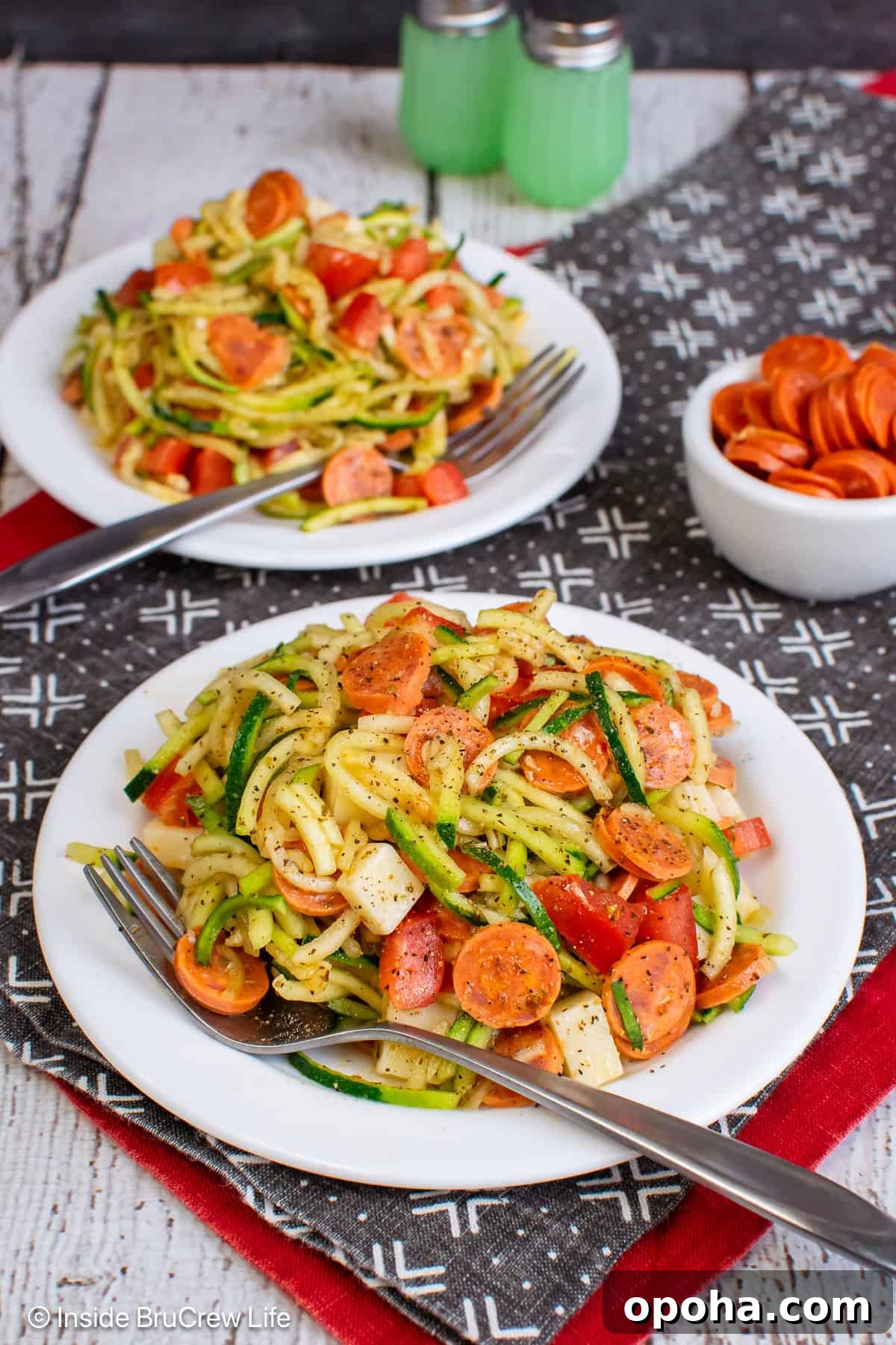 Two white plates with pizza zucchini noodle salad on it.