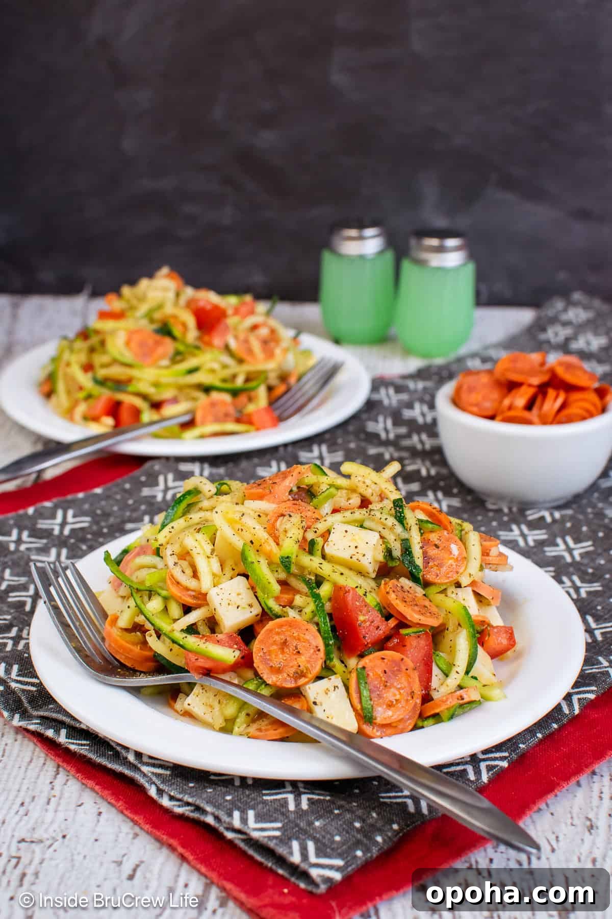 Two white plates with pizza zucchini noodle salad on it.