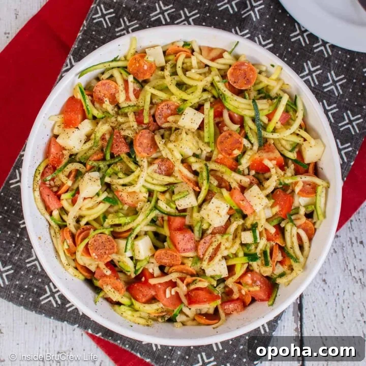 An overhead picture of a large bowl of zucchini noodle salad with pizza toppings.
