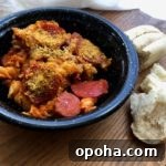 Black bowl of meat lovers pasta with bread on side