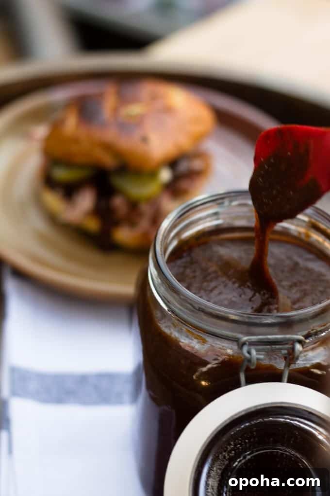 pumpkin spice bbq sauce dripping from utensil and pulled pork sandwich in background