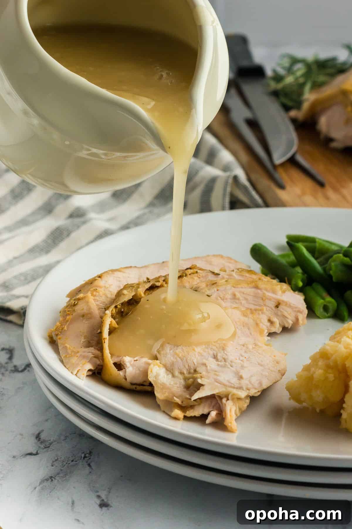 Gravy being poured onto a plate of slow cooker turkey breast.
