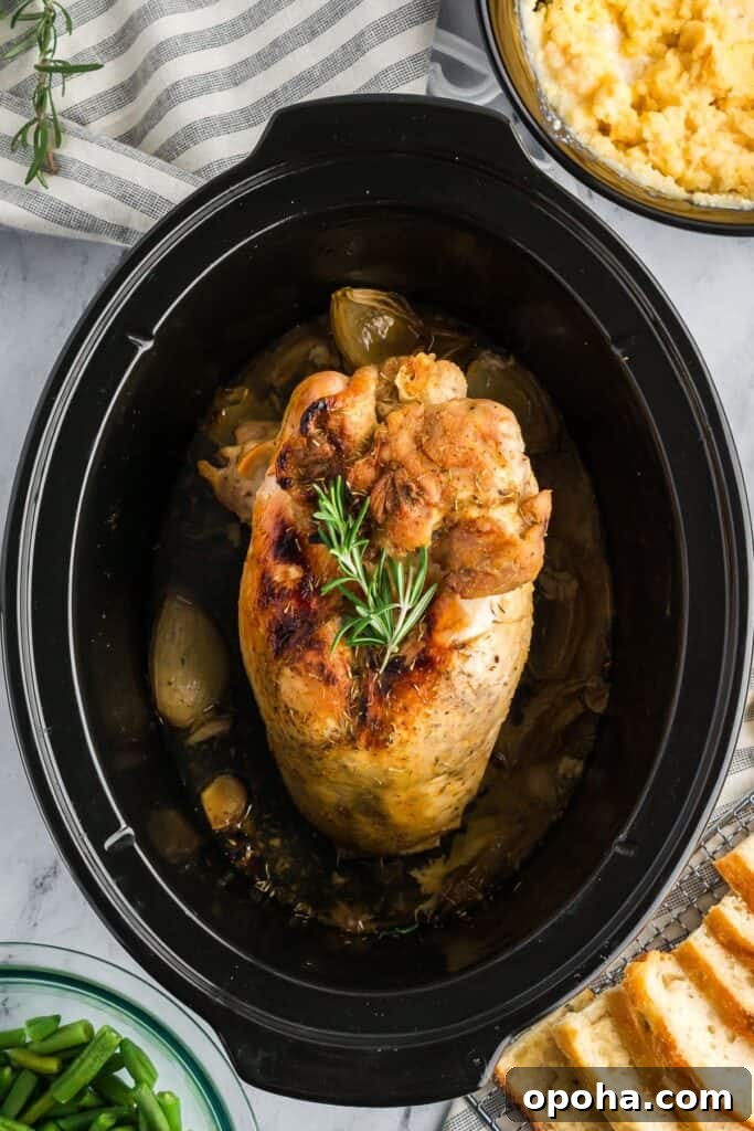 Perfectly cooked turkey breast with a golden crust and rosemary garnish in a slow cooker, ready to serve.