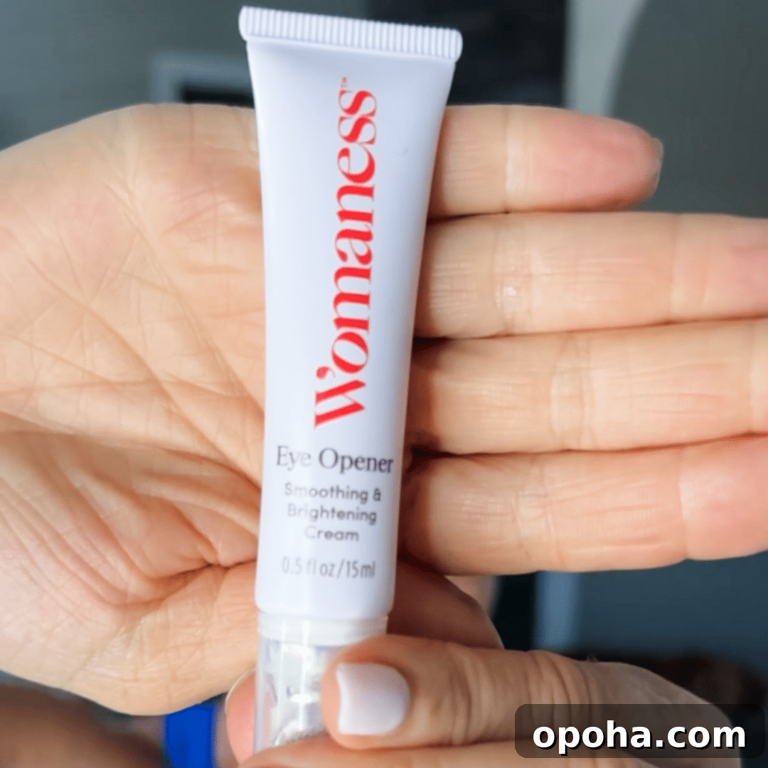 Top Anti-Aging Skincare Picks for Women Over 50 2 Woman holding up a white bottle of Womaness Eye Opener cream with hand behind the product.