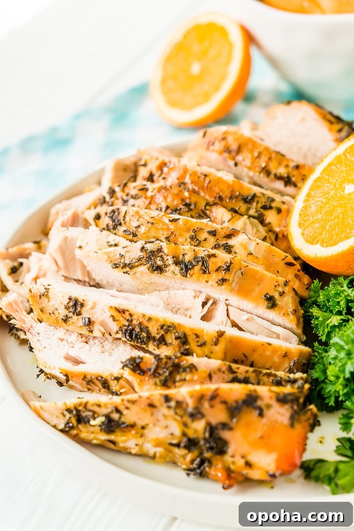 Juicy Slow-Cooker Turkey Breast Recipe for Tender Results 3 Sliced Turkey Breast with herbs on a white plate with half an orange and parsley in the background.