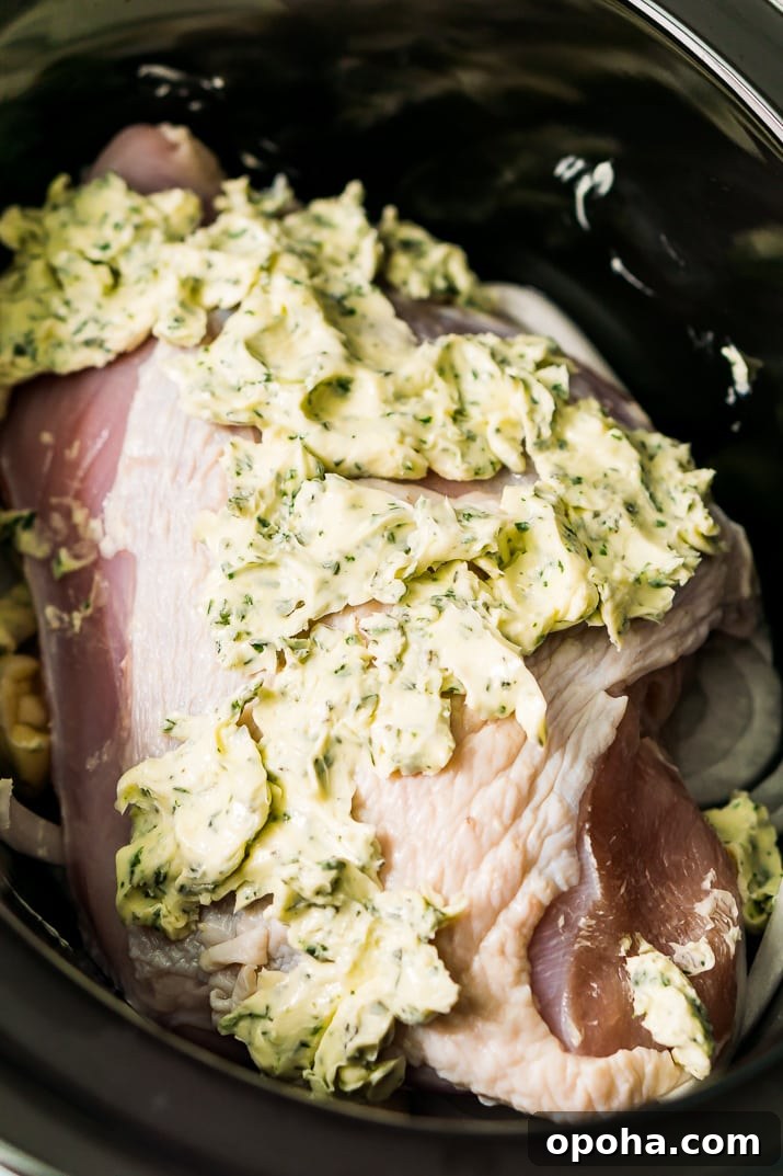 Juicy Slow-Cooker Turkey Breast Recipe for Tender Results 6 Turkey breast in a slow cooker covered in herb butter.