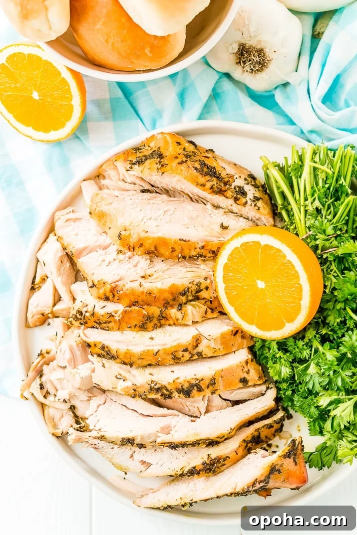Juicy Slow-Cooker Turkey Breast Recipe for Tender Results 7 Overhead photo of a turkey breast covered in herbs and sliced on a plate with oranges and parsley.