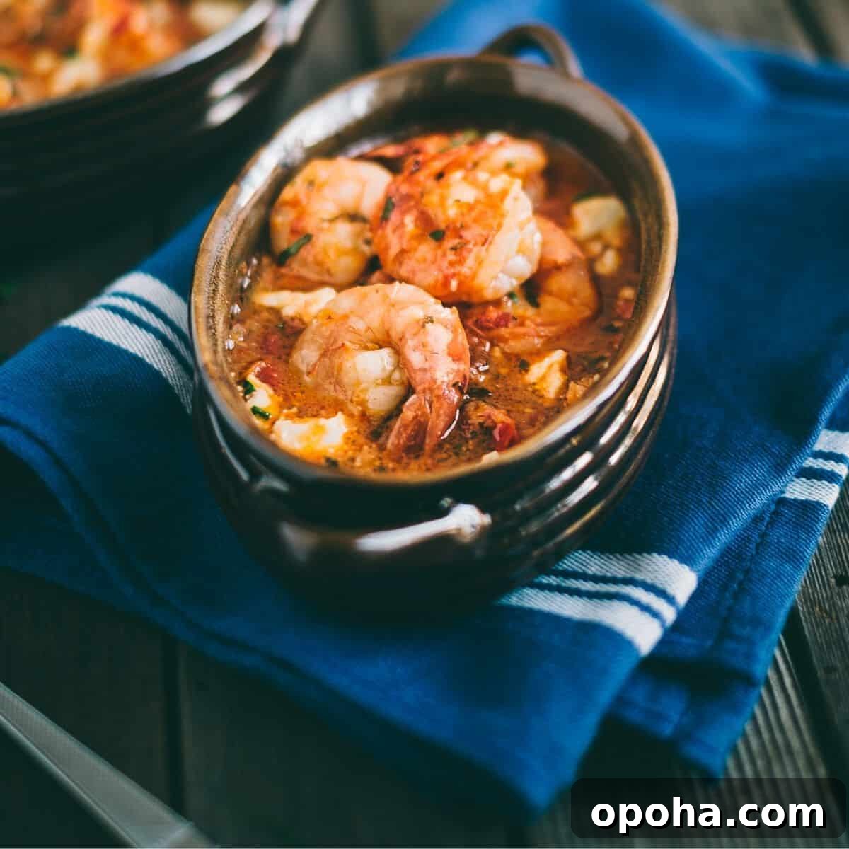 cooked prawns in a tomato sauce served in an oval ceramic dish