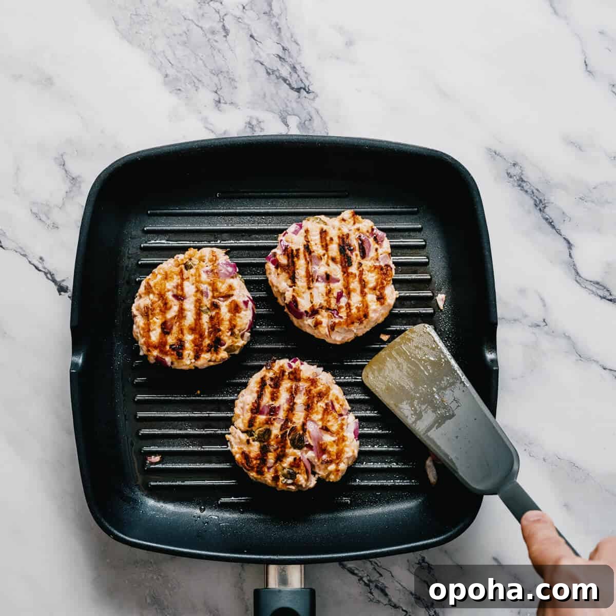cooking salmon burgers in a grill pan.