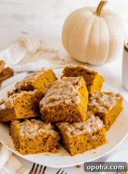 plate of pumpkin coffee cake square with icing and white pumpkin behind plate