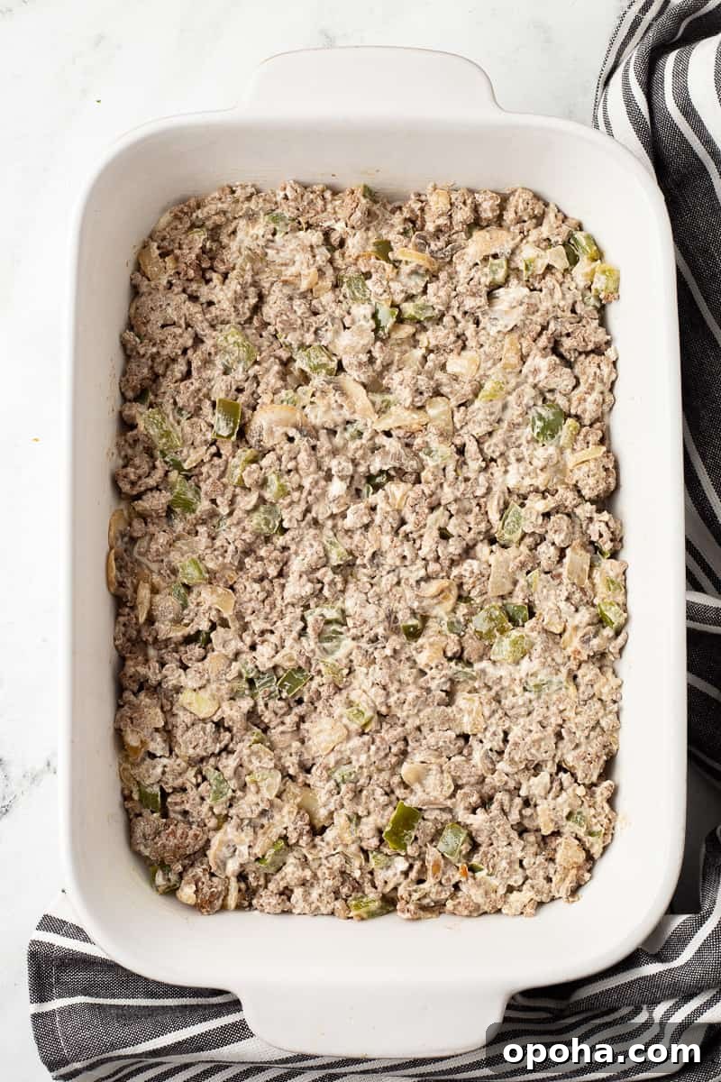 Philly Cheesesteak Casserole with Ground Beef — Savory Comfort Bake 11 Ground beef mixture with cream cheese is spread on top of the biscuit crust.