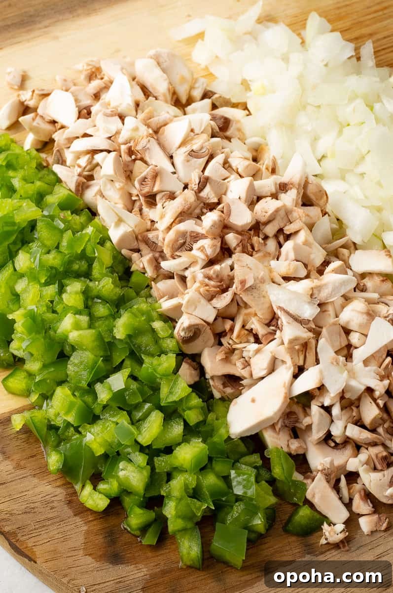 Philly Cheesesteak Casserole with Ground Beef — Savory Comfort Bake 5 Chopped green pepper, mushrooms and onions on a wooden board.