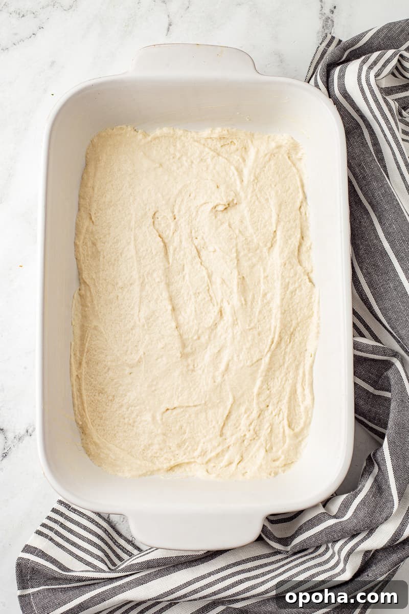 Philly Cheesesteak Casserole with Ground Beef — Savory Comfort Bake 7 Bisquick mix has been mixed with 1 cup of water and spread into the bottom of 9x13-inch baking dish.