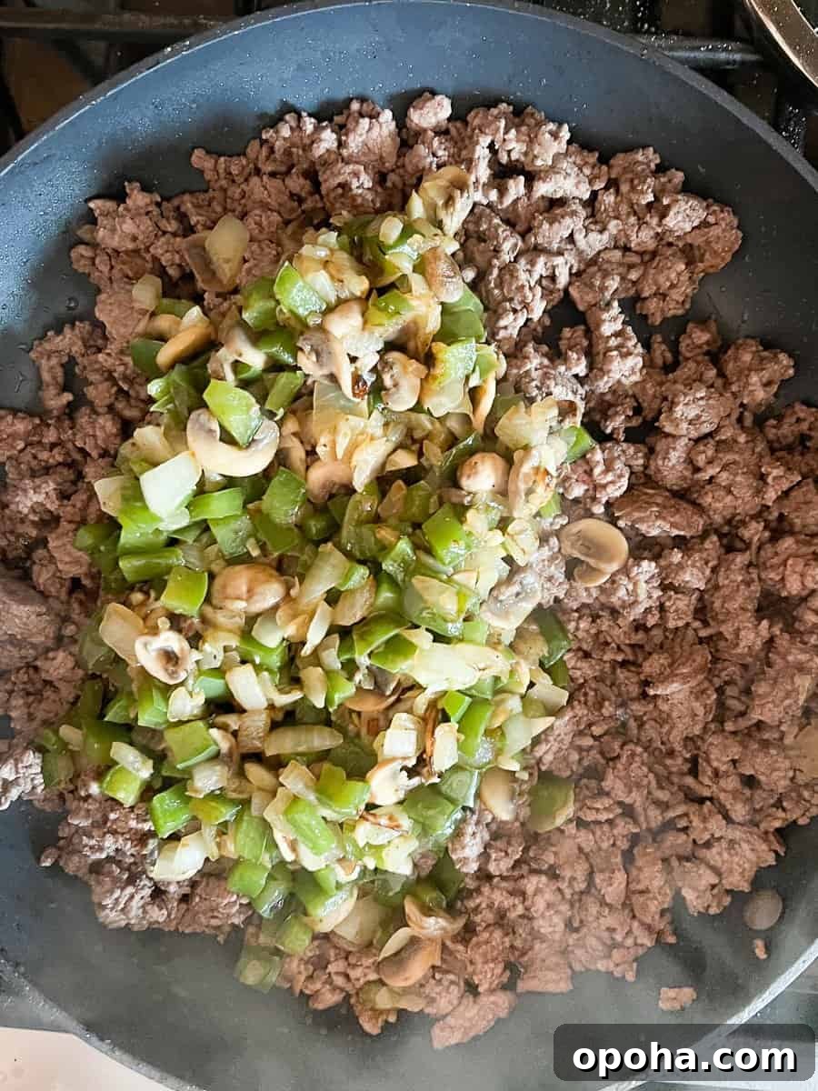 Philly Cheesesteak Casserole with Ground Beef — Savory Comfort Bake 9 Cooked vegetables are added to the cooked ground beef in large skillet.
