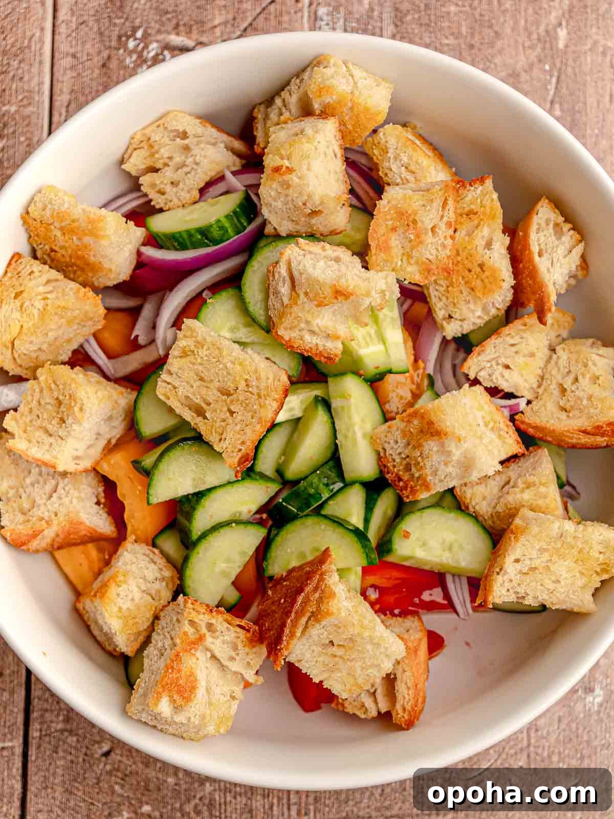 Tuscan Panzanella Salad: Classic Bread & Tomato Recipe 5 Bread, cucumbers and tomatoes in a bowl.