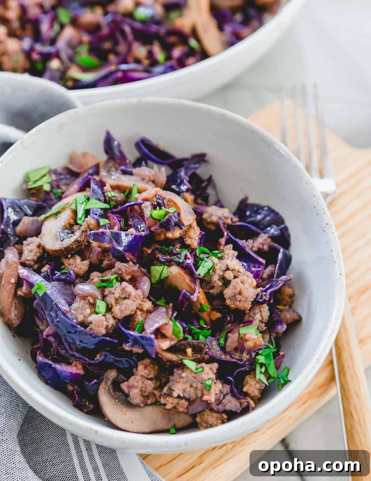 Pork and cabbage stir fry in a ceramic bowl on a cutting board. Pork and cabbage stir fry in a ceramic bowl on a cutting board.