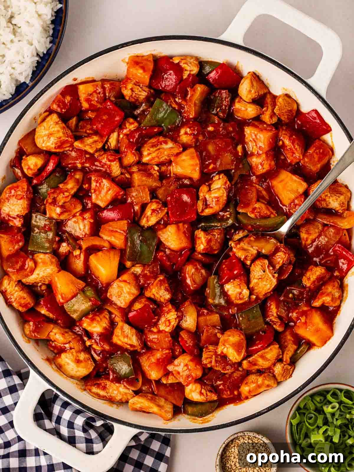 Sweet and Sour Chicken Recipe — Quick Home-Style Version 2 A white pan on a dining table filled with cooked Sweet and Sour Chicken, ready to serve.