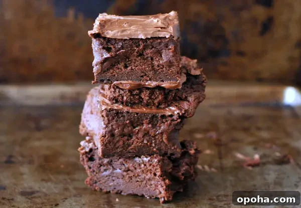 a stack of four frosted vegan brownies against a dark marbled background