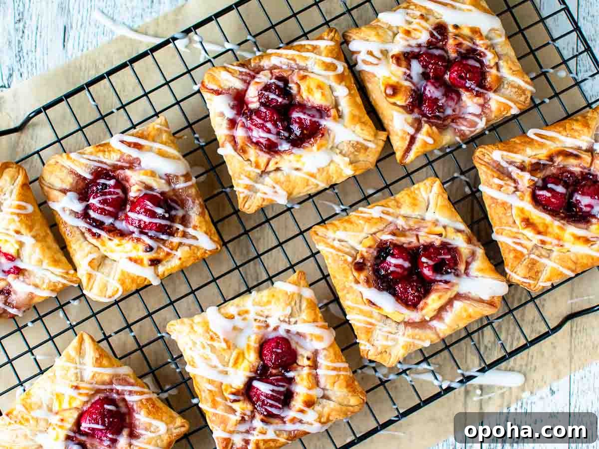 Raspberry Danish Recipe: Flaky Pastry with Fresh Raspberry Filling 8 Raspberry pastries on black wire rack viewed from above.