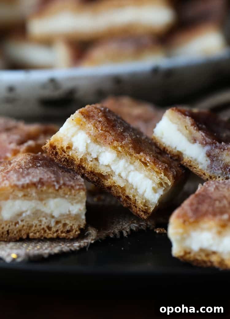 Sopapilla Cheesecake Bars Assorted sopapilla cheesecake bars stacked next to a plate.