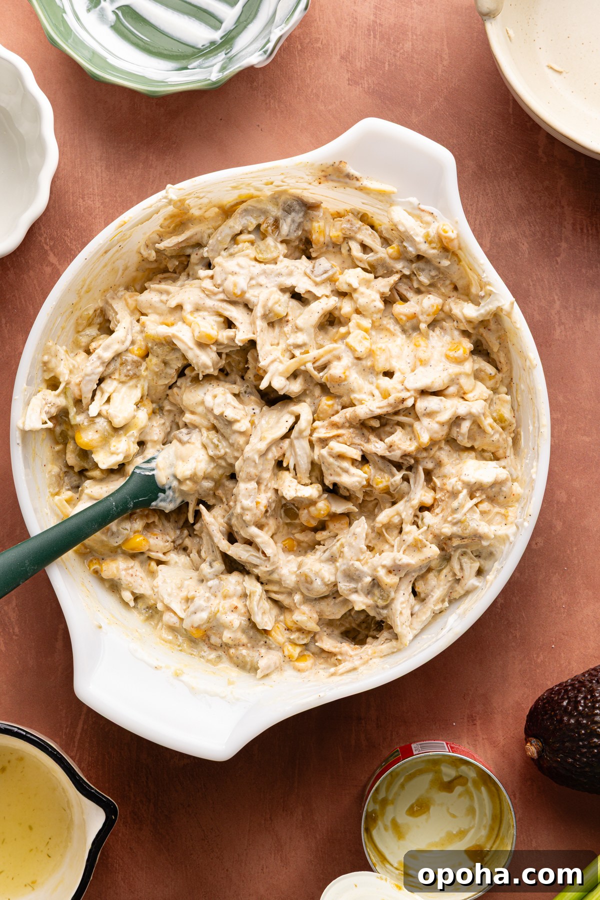 A large bowl filled with a cheesy chicken enchilada dip ready to be baked in the oven